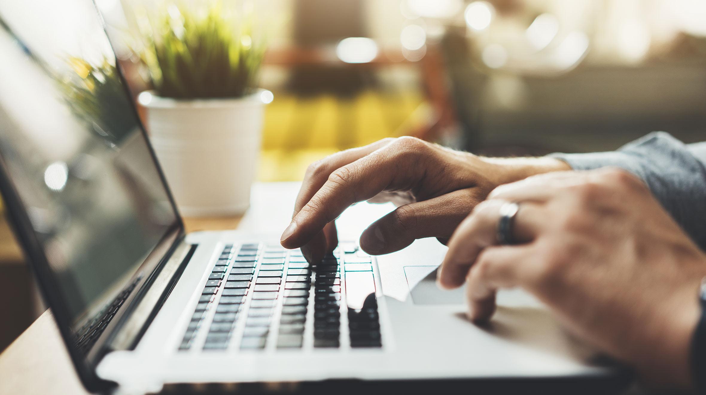 Close-up of hands typing on a laptop keyboard.