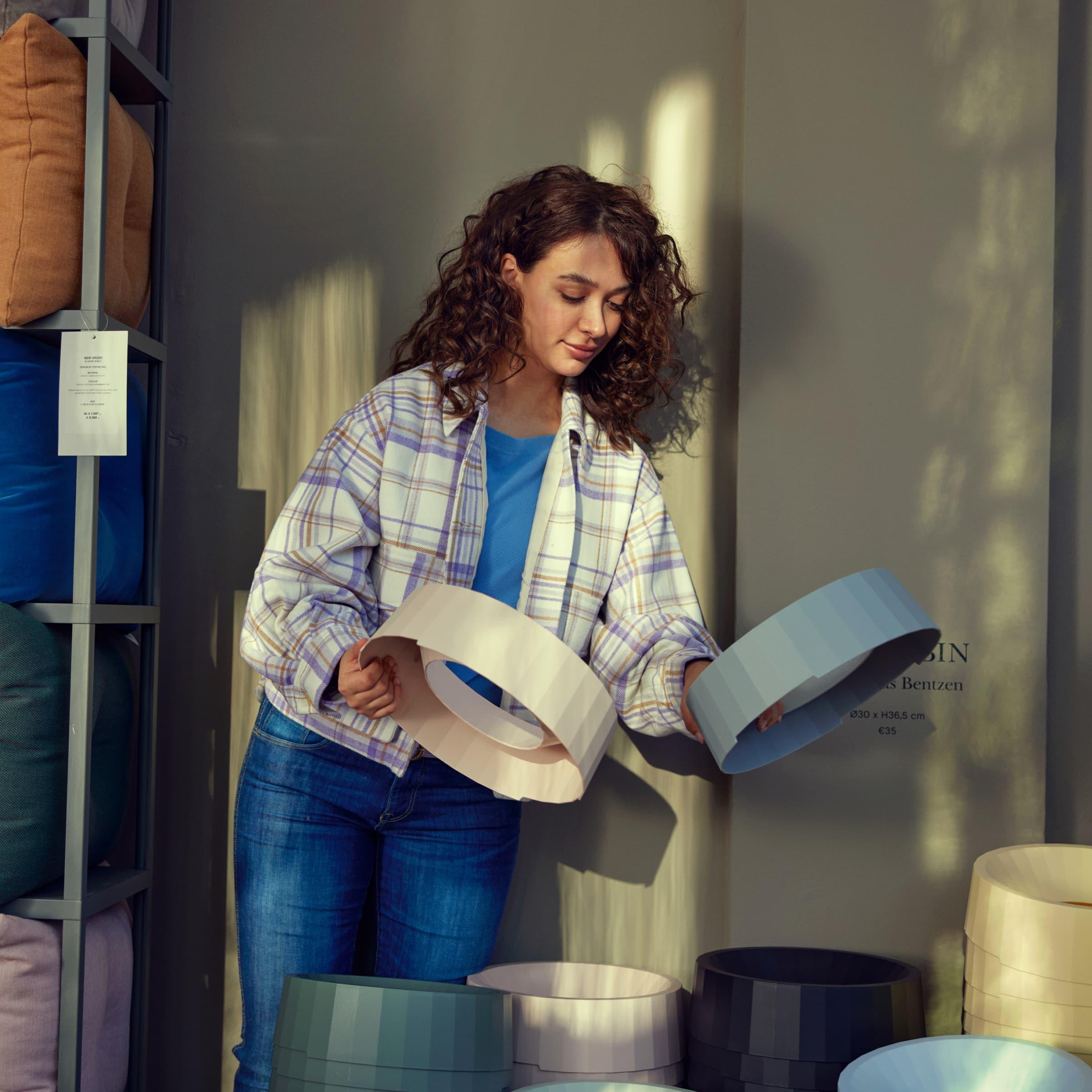 A person examining lampshades at a home goods store.