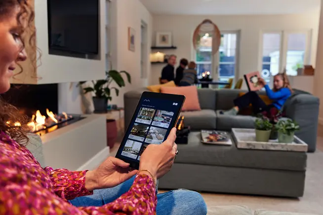 A woman in a living room choosing a restaurant to book on her tablet.