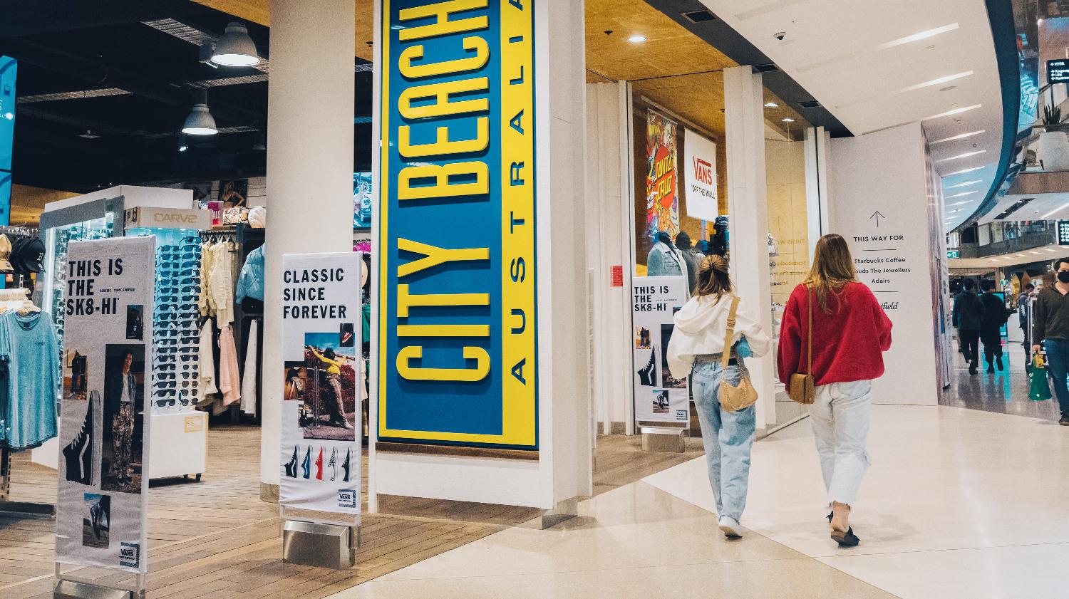 Shoppers walking past the City Beach store in a busy mall corridor