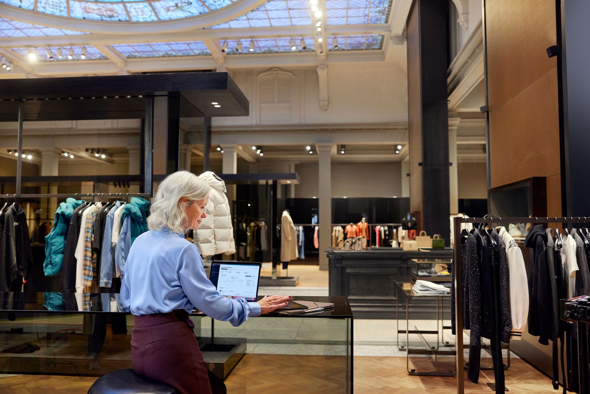 Um funcionário de uma loja de moda de luxo olhando o painel de pagamentos no seu laptop.