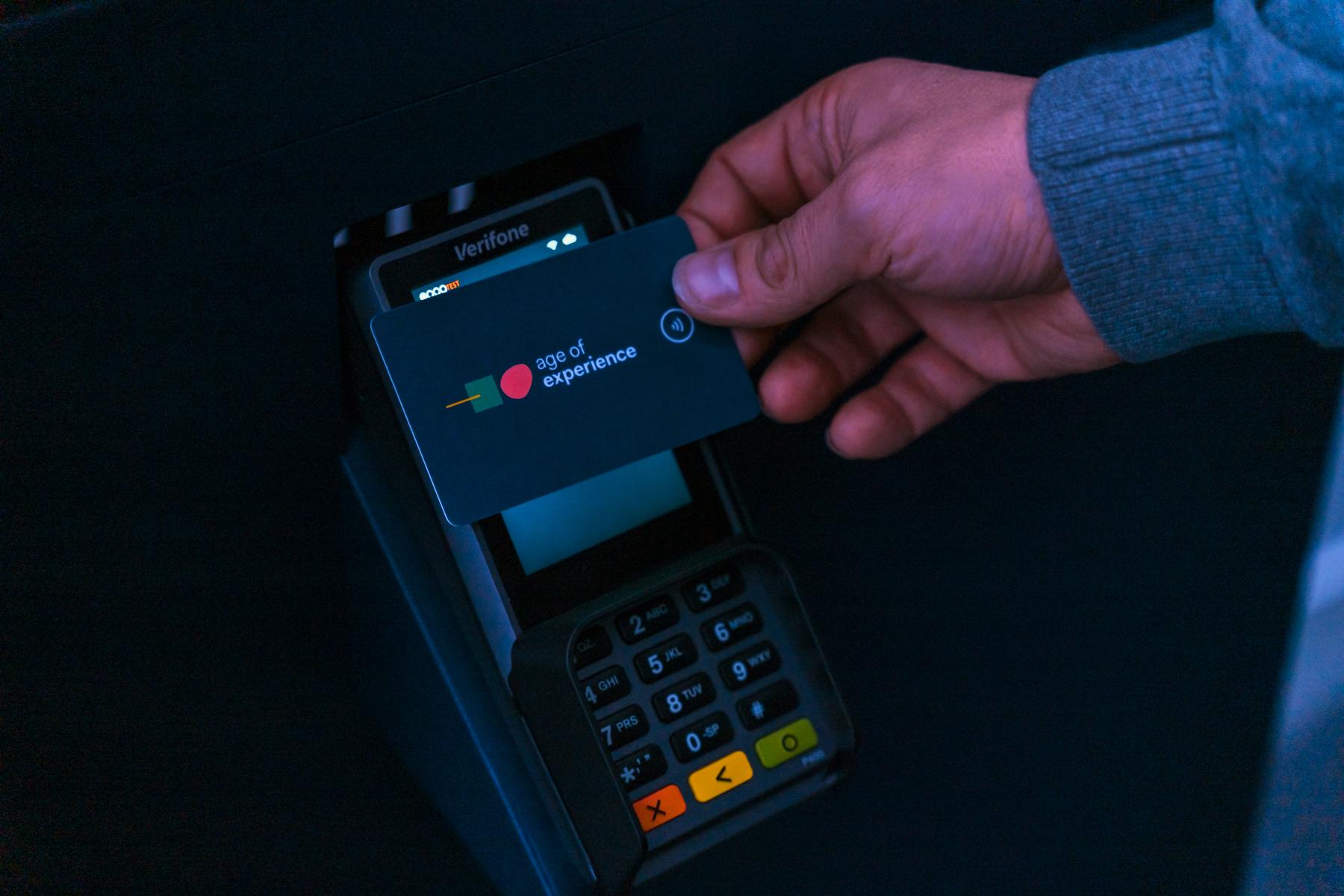 Main tenant une carte avec le logo Adyen vers un terminal de paiement.