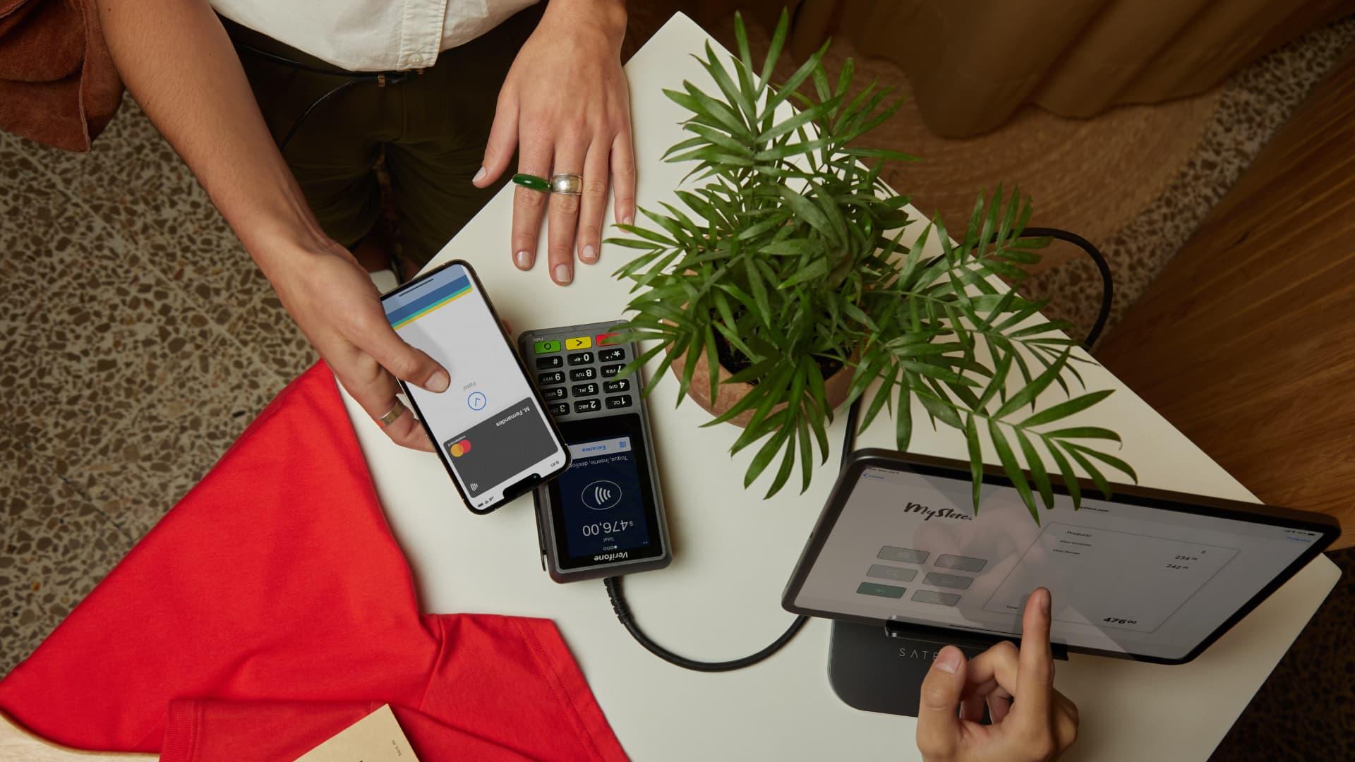 Person using a mobile phone to make a contactless payment on an Adyen payment terminal.