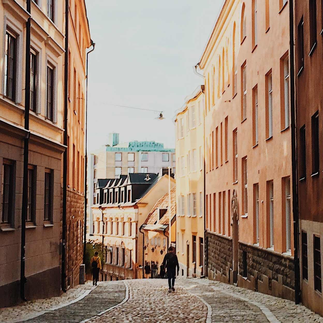 Kullerstensgata i gamla staden med historiska byggnader och gående människor