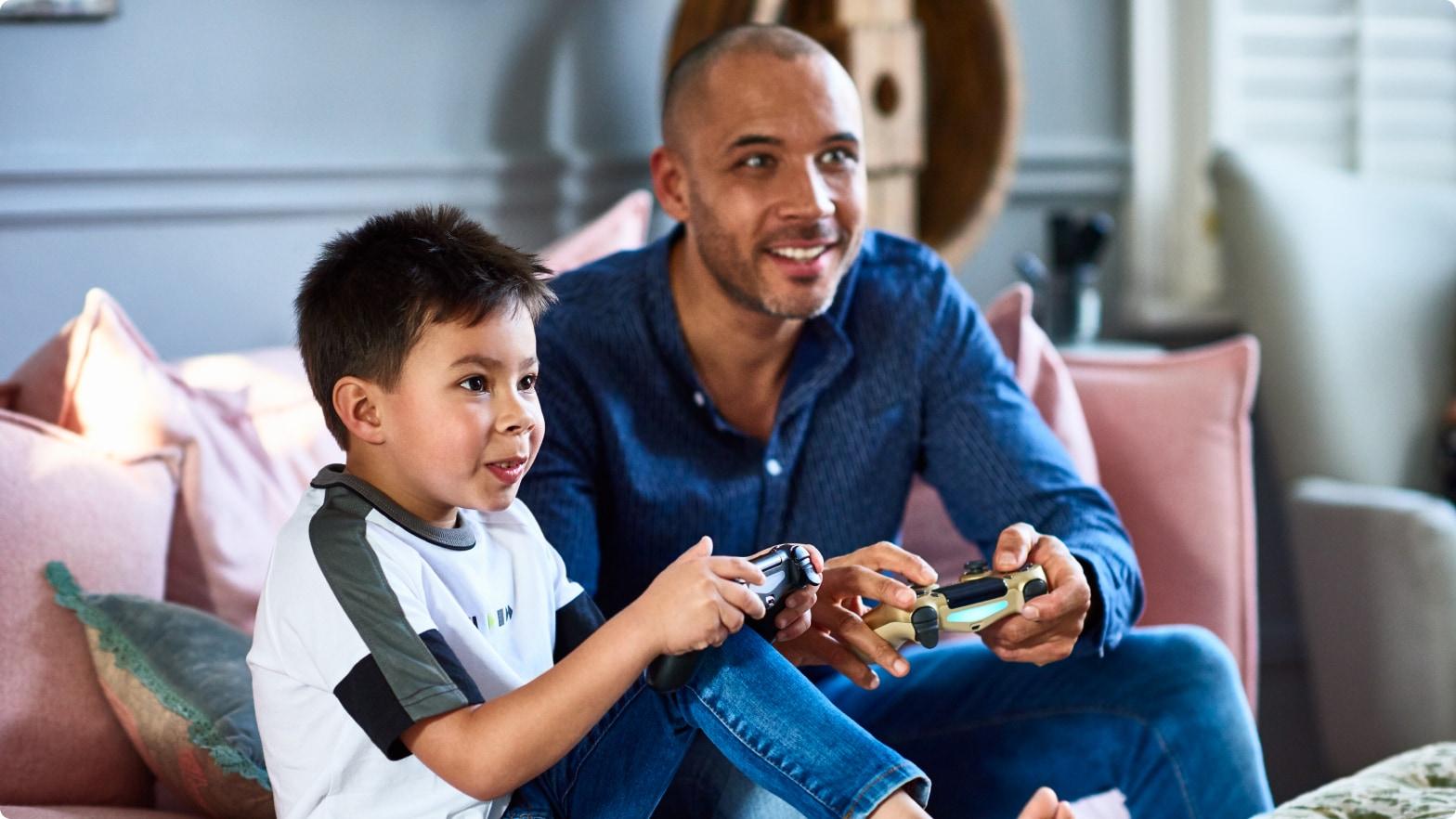 A child and an adult playing video games together on a couch.