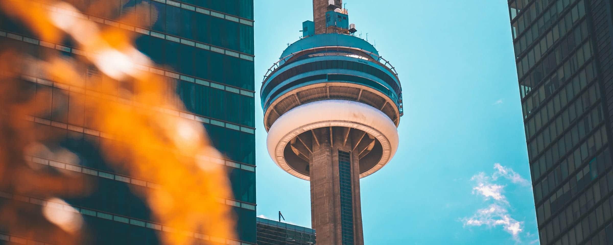 Observationsturm flankiert von Wolkenkratzern unter blauem Himmel.