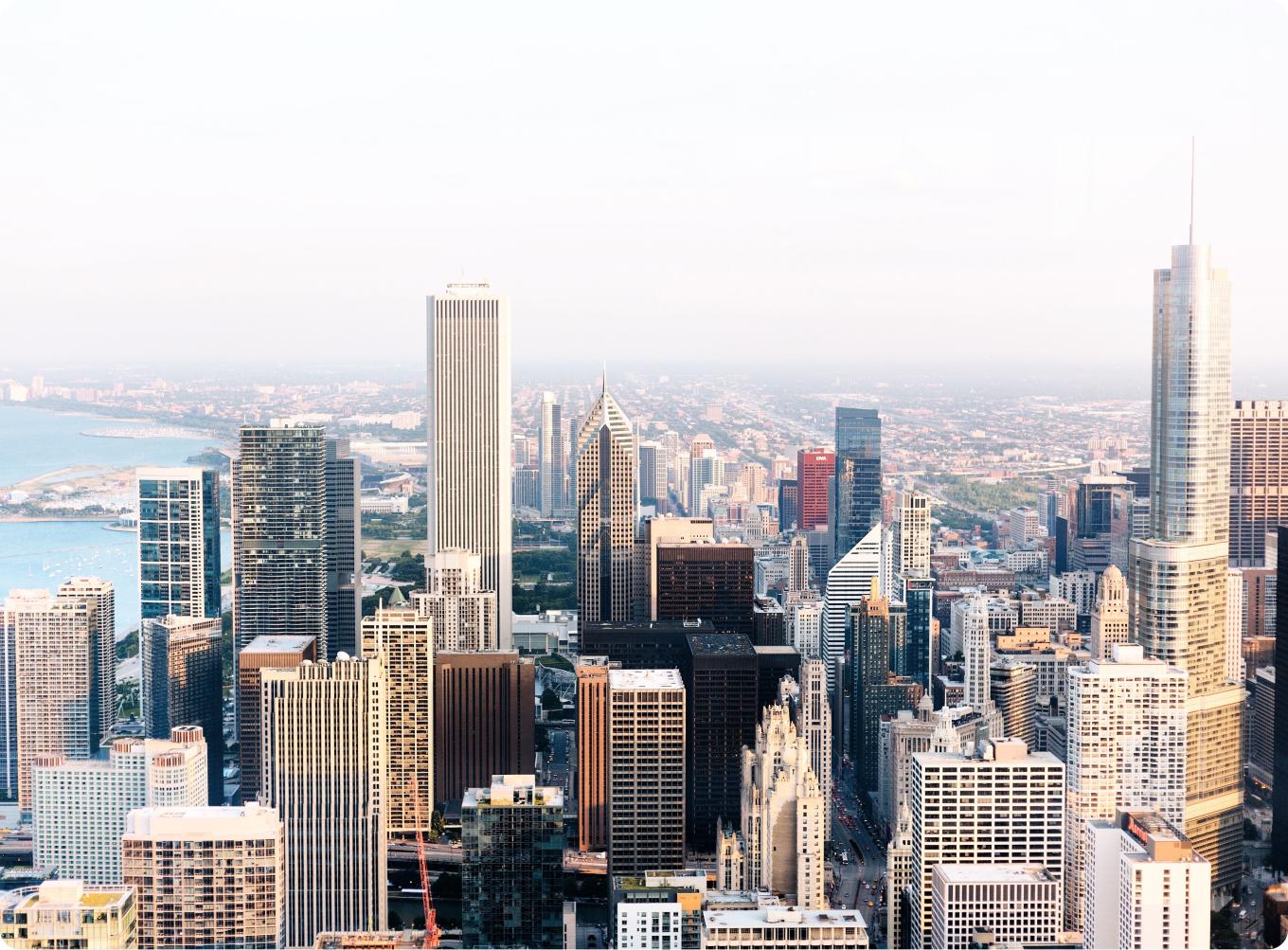 Aerial view of Chicago city skyline with skyscrapers and coast in the background.