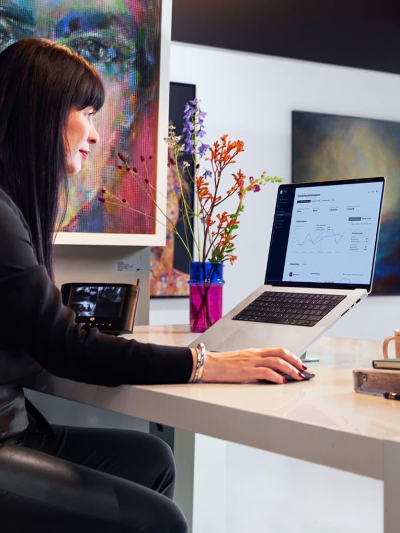 Osoba analizująca analizy Adyen na ekranie laptopa z kolorową sztuką w tle