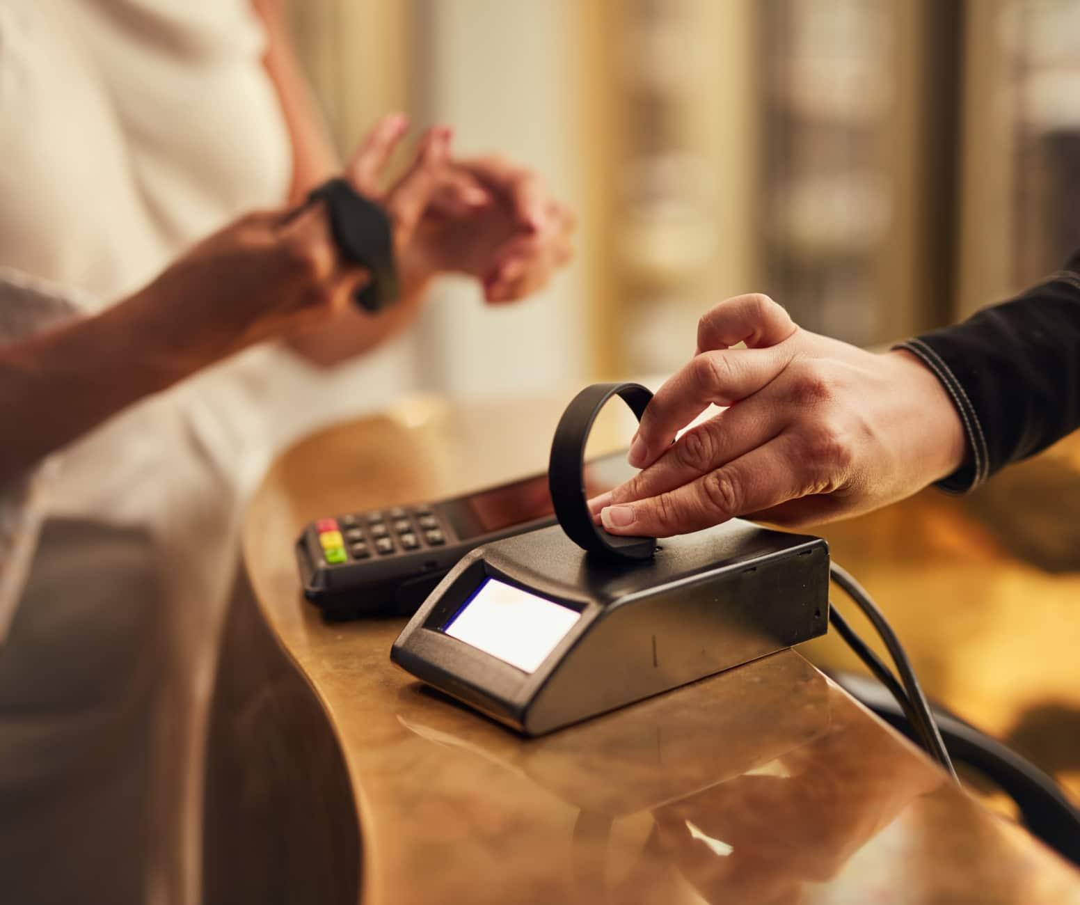 Personne utilisant un dispositif intelligent portable pour effectuer un paiement sans contact sur un terminal Adyen.