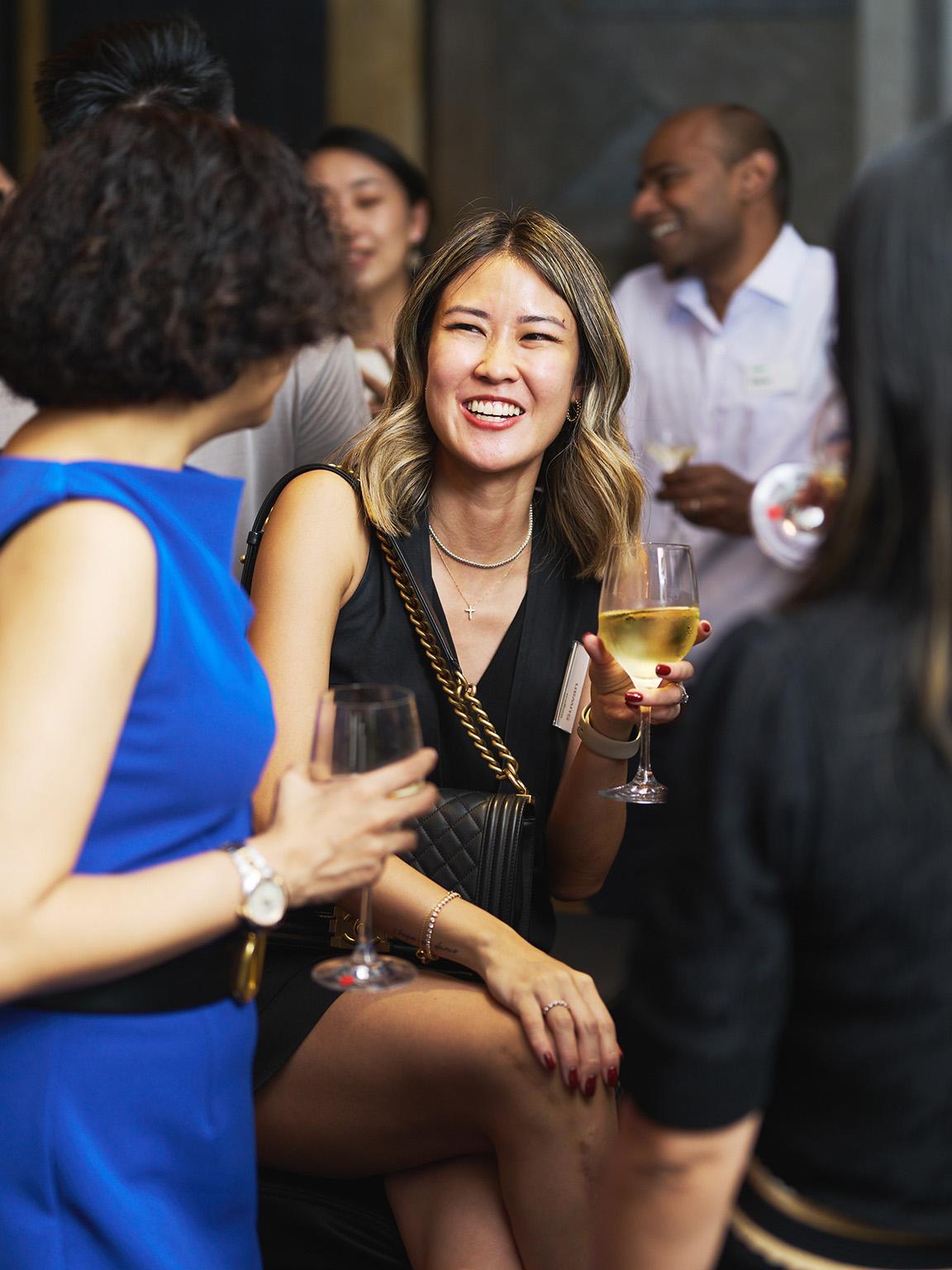 A smiling woman holding a glass of champagne at a social event.