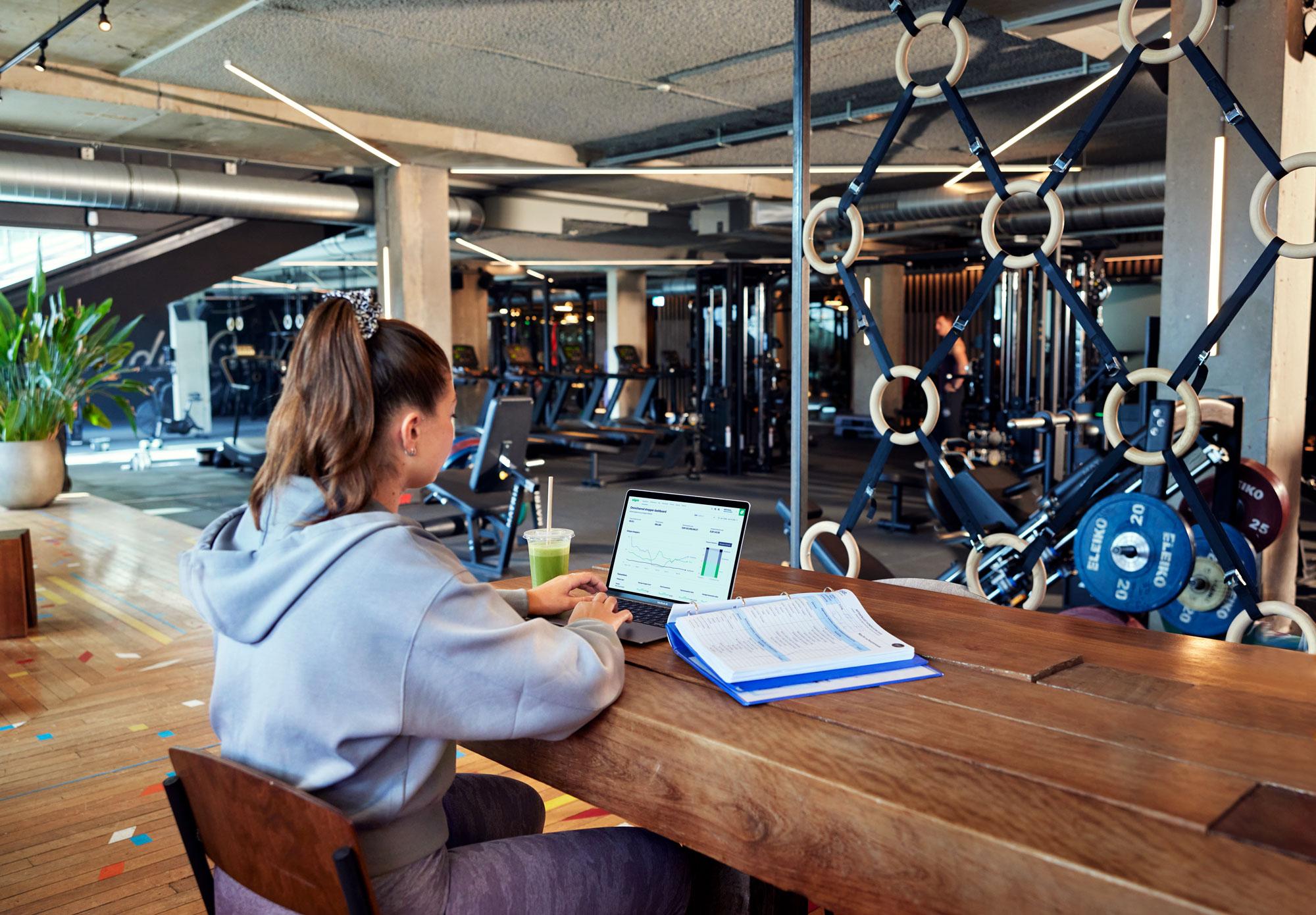 Zaměstnanec fitness centra prohlíží Adyen dashboard s datovými grafy.