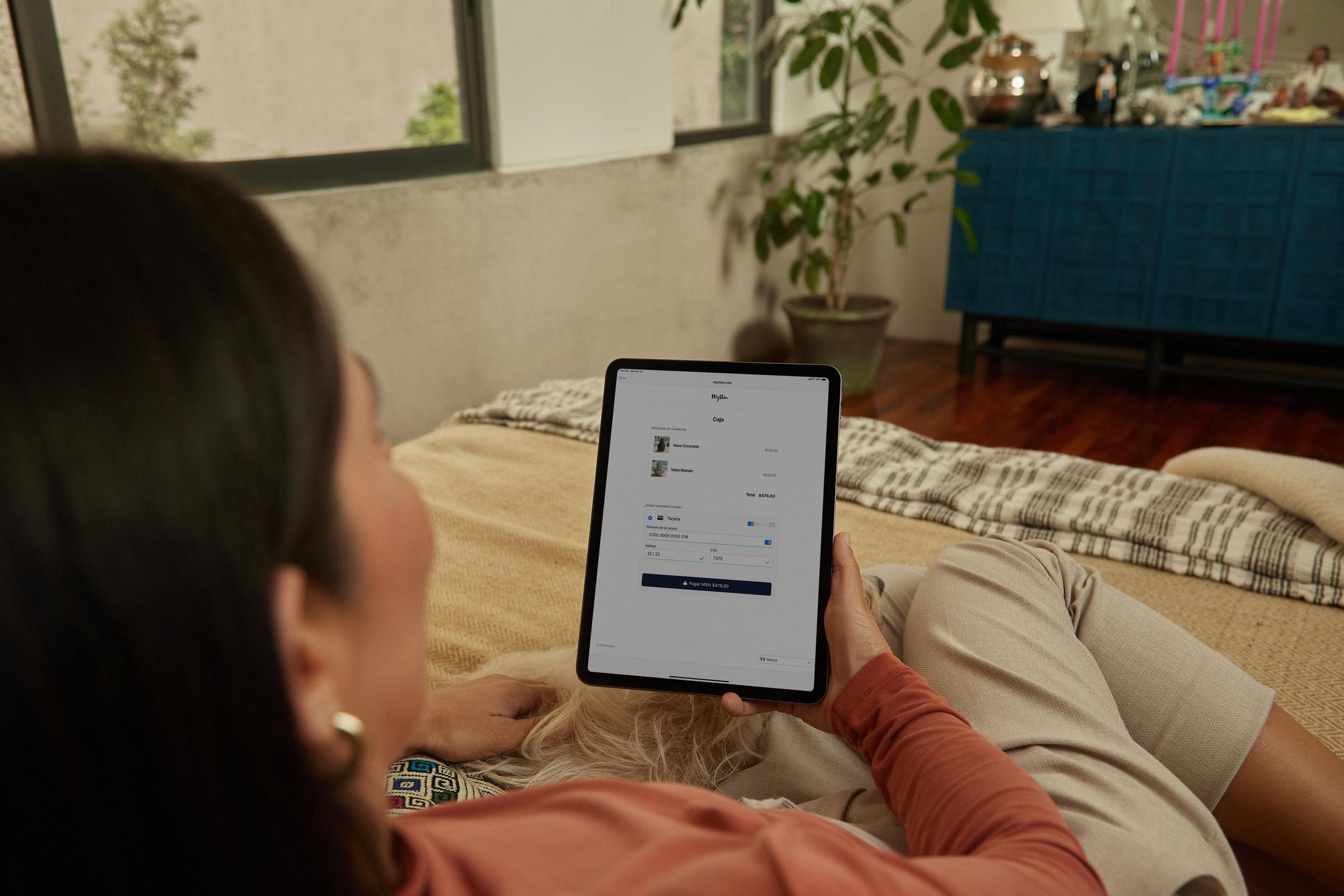 Person reclining with a tablet showcasing Adyen checkout interface.