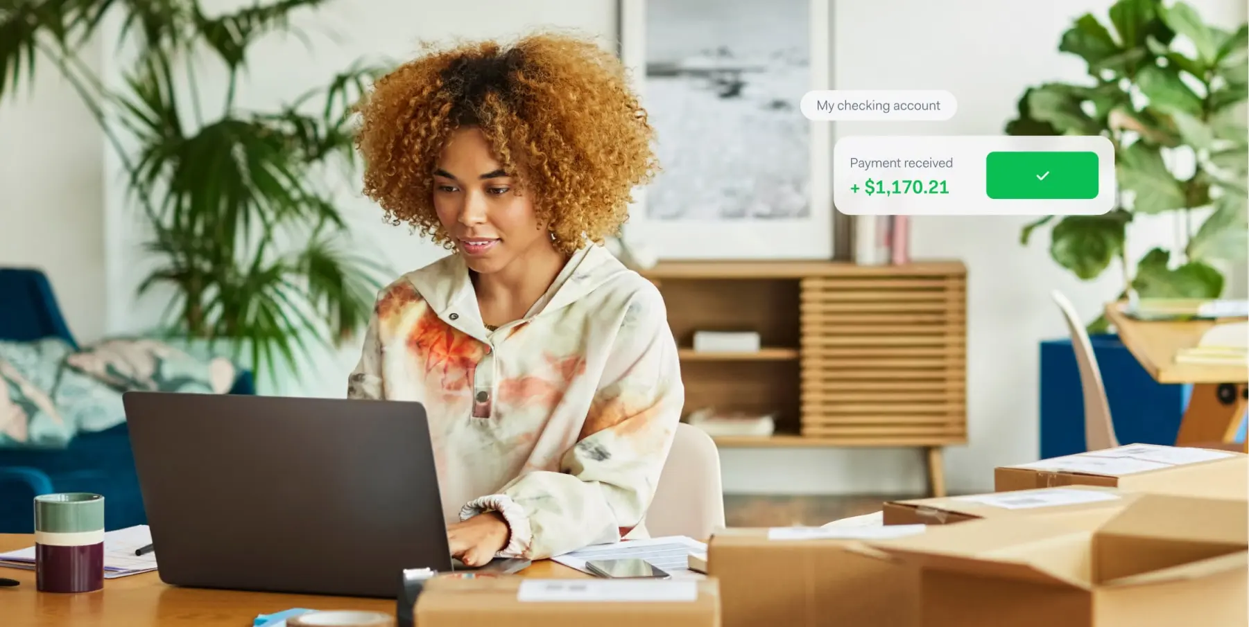 Mujer trabajando en portátil con notificación de pago de Adyen de $1,170.21 recibida en pantalla.