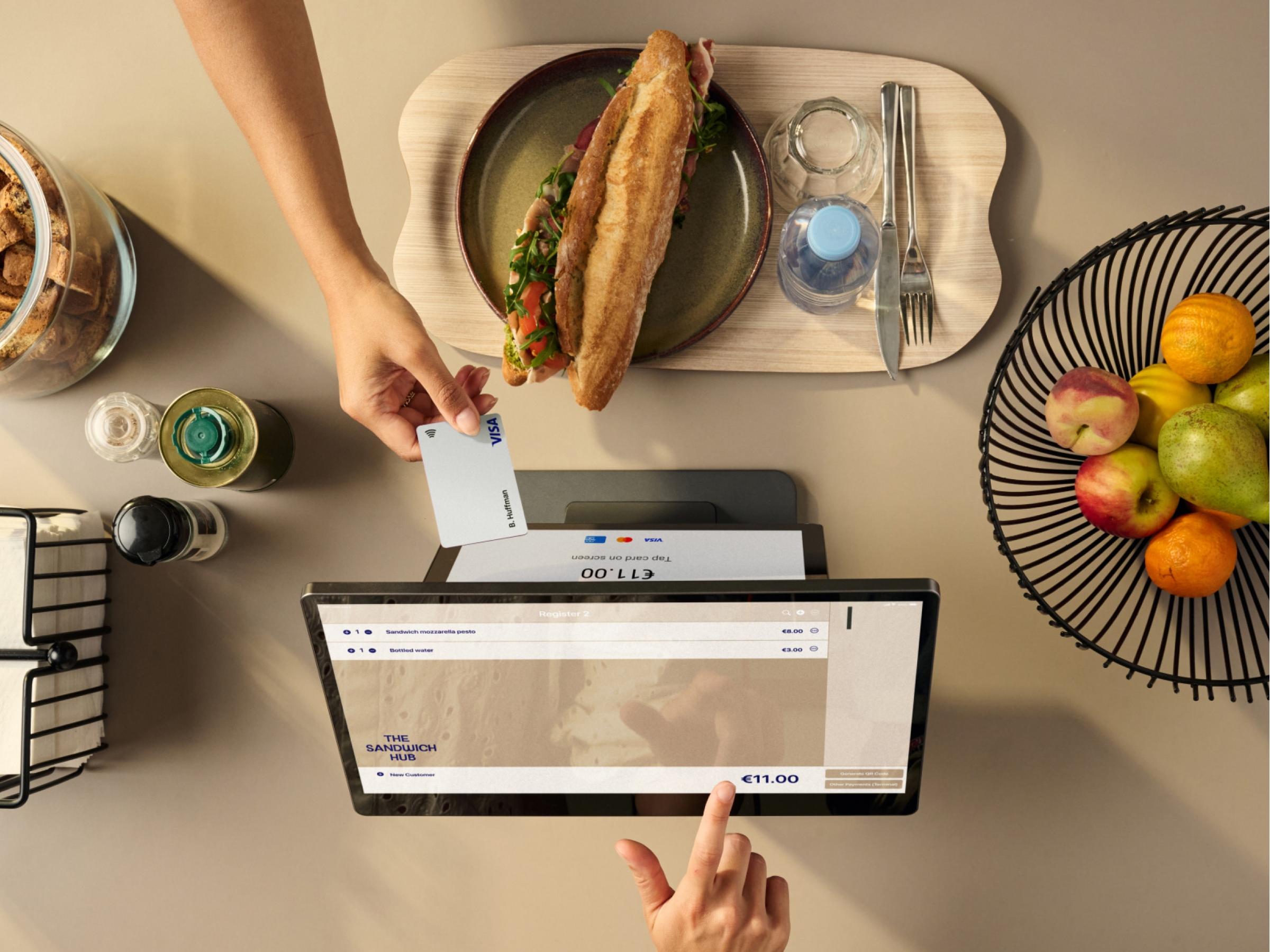 Person paying with a contactless card on an Adyen payment terminal at a restaurant.