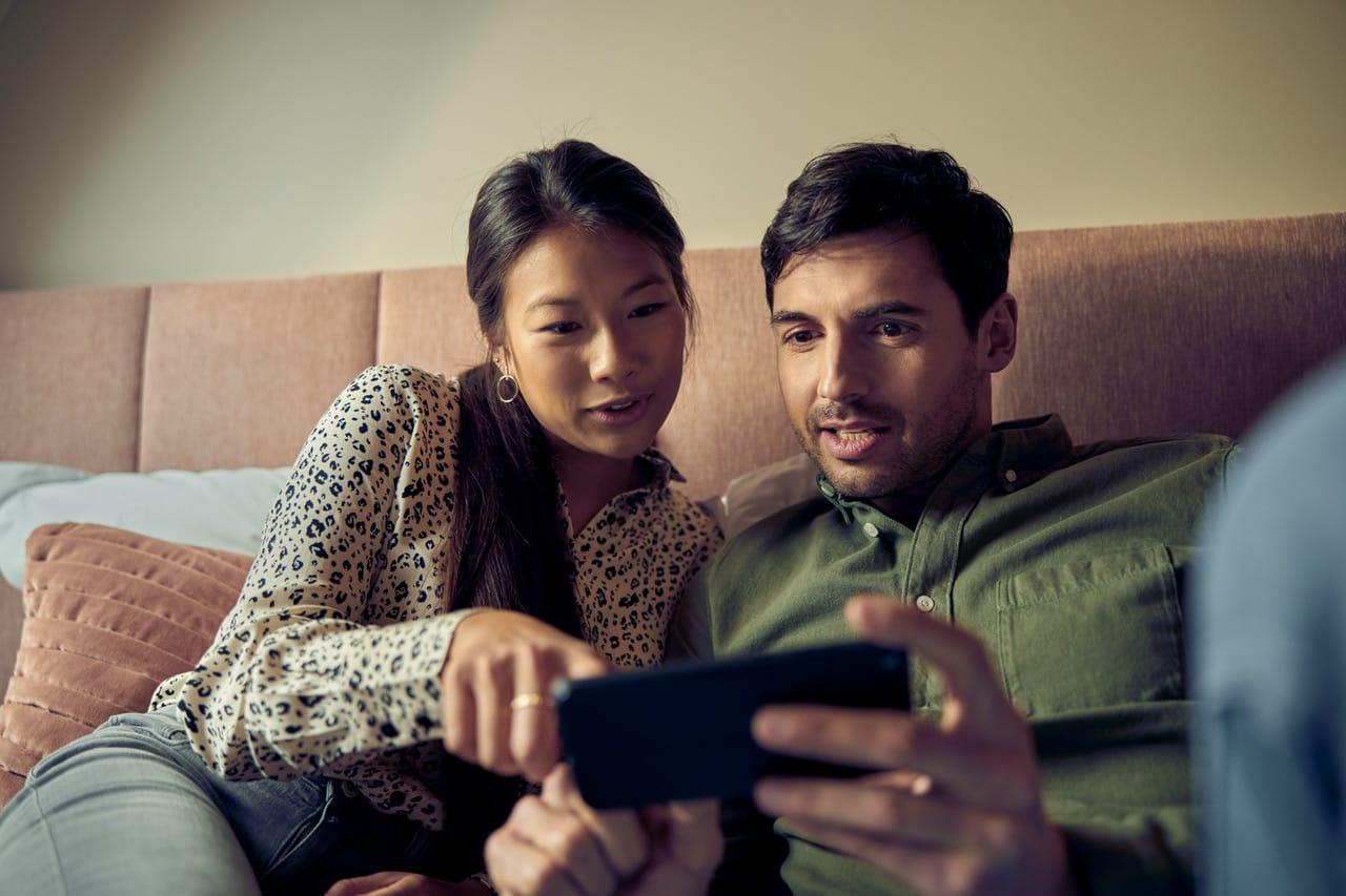 Two individuals closely reviewing content on a smartphone together.