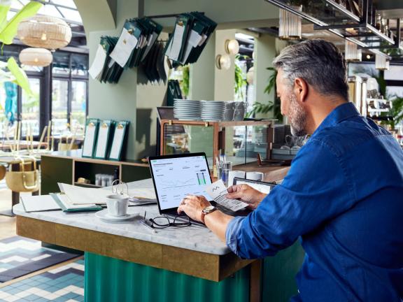 A man behind a laptop in a restaurant setting