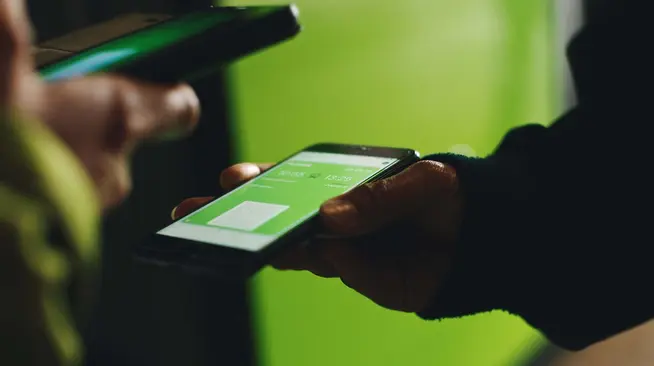Close-up of a hand holding a smartphone displaying a payment transaction on Adyen app.