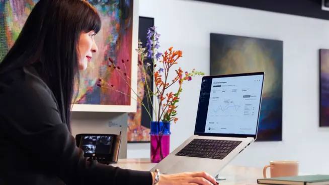 Woman reviewing Adyen analytics on laptop in art gallery