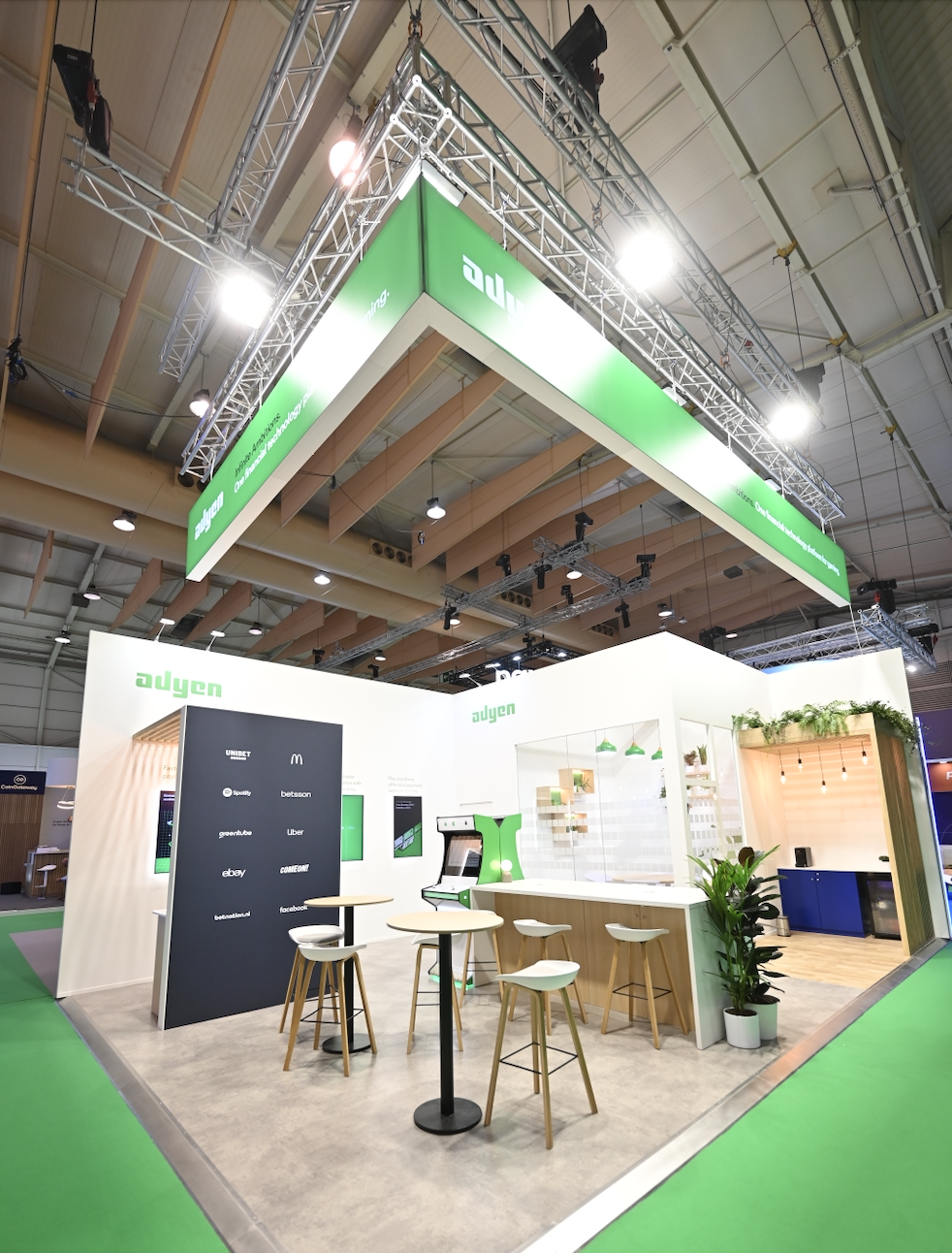 Adyen's booth at a tradeshow, featuring demo screens and networking areas.