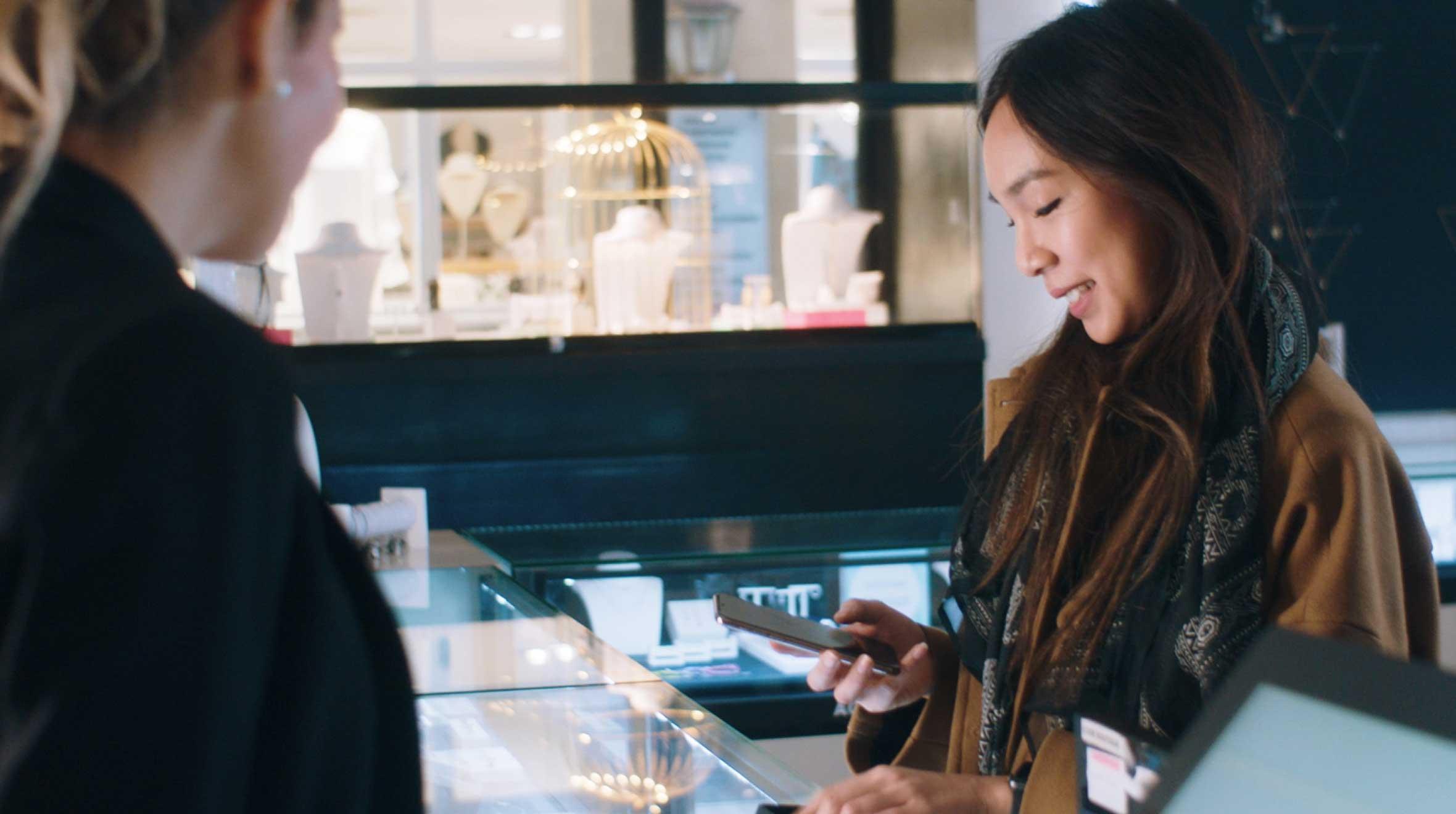 Femme utilisant un smartphone pour effectuer un paiement dans un magasin de détail.