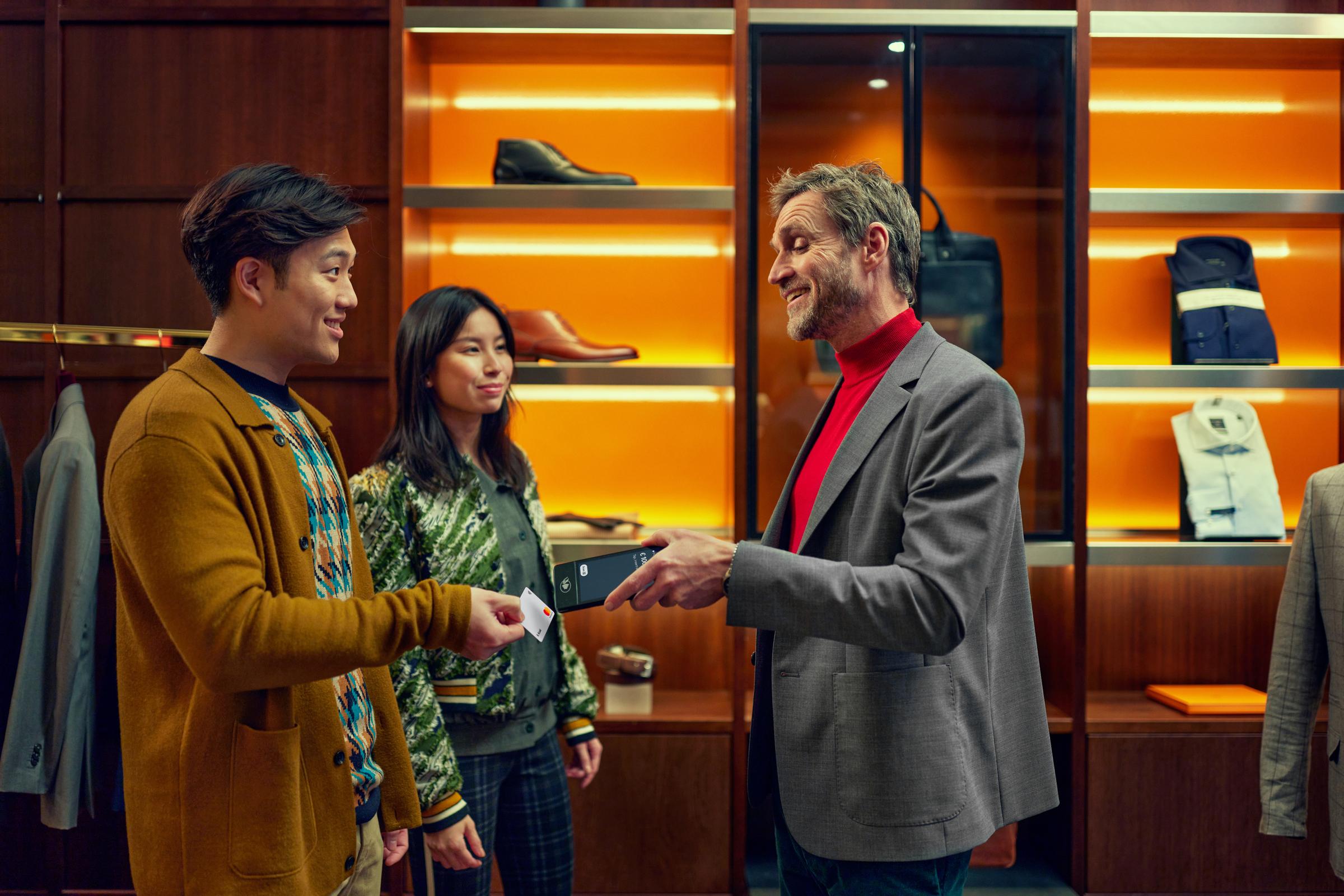 Mann und Frau zahlen mit Karte in einem Luxuskleidungsgeschäft.