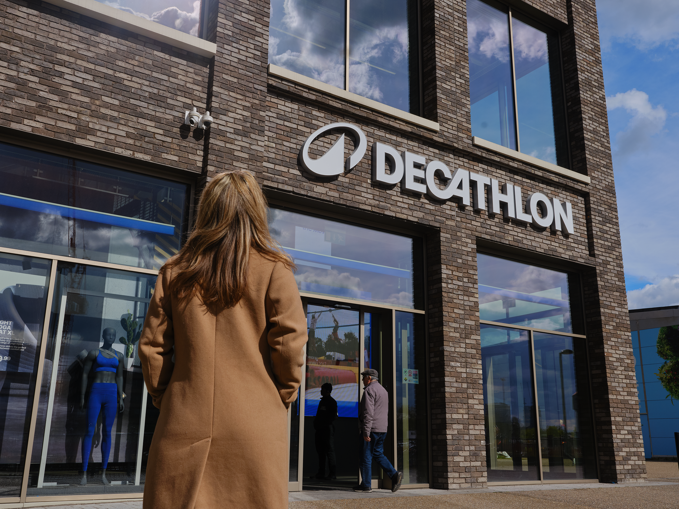 A woman standing in front of a Decathlon store.
