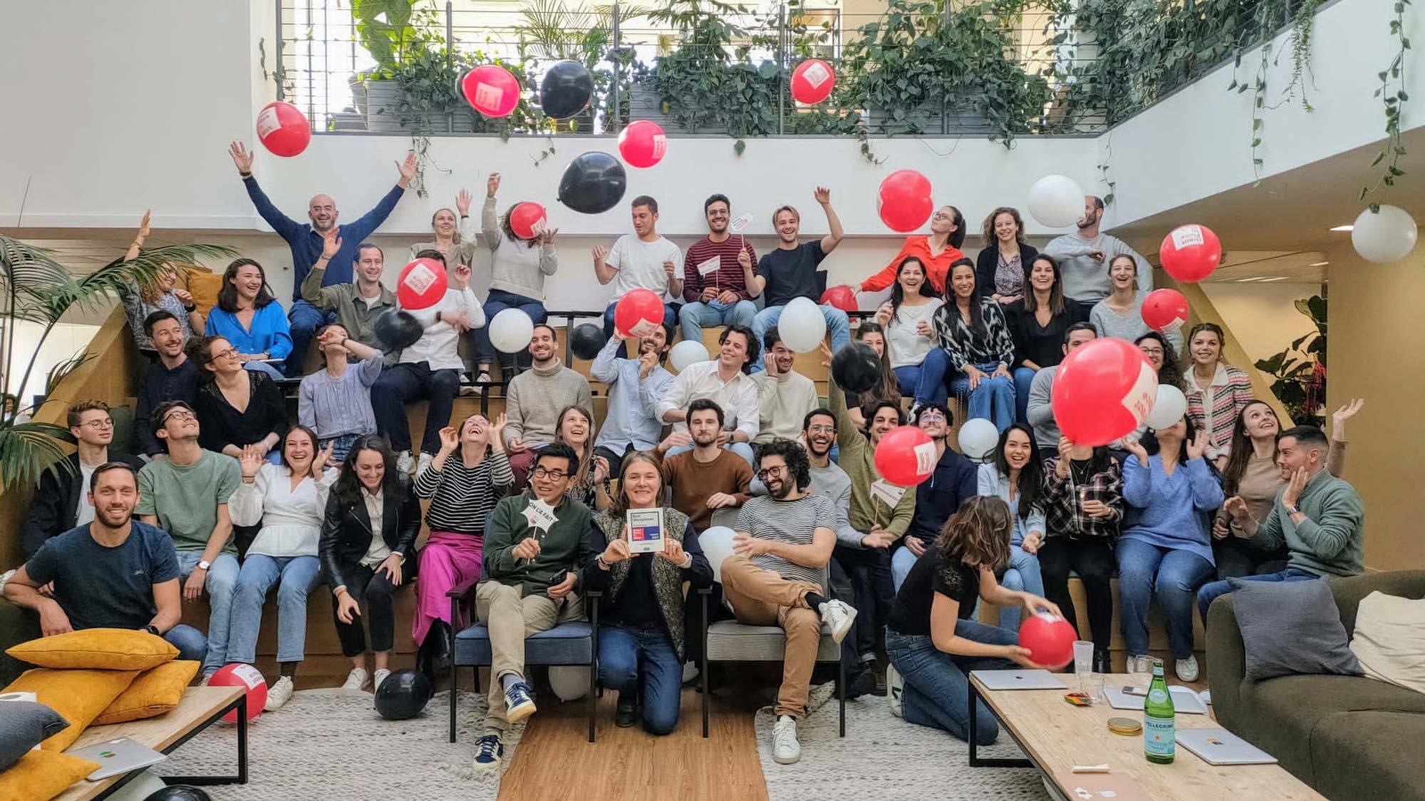 Groupe de personnes joyeuses célébrant avec des ballons et montrant une certification.