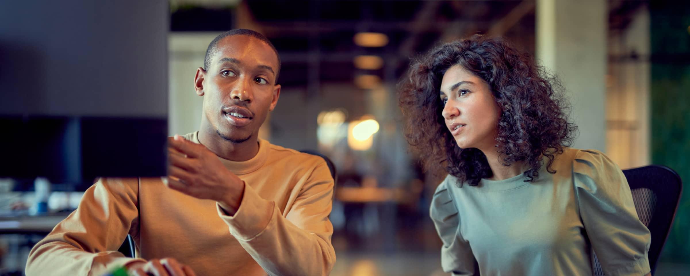 Two professionals in a discussion at a modern workplace.