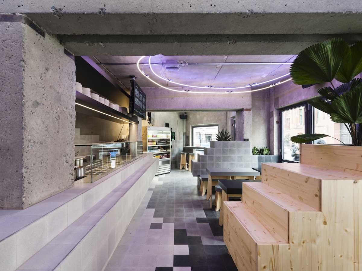 Modernes Café-Innenleben mit violetten Neonleuchten und Holzsitzbereich.