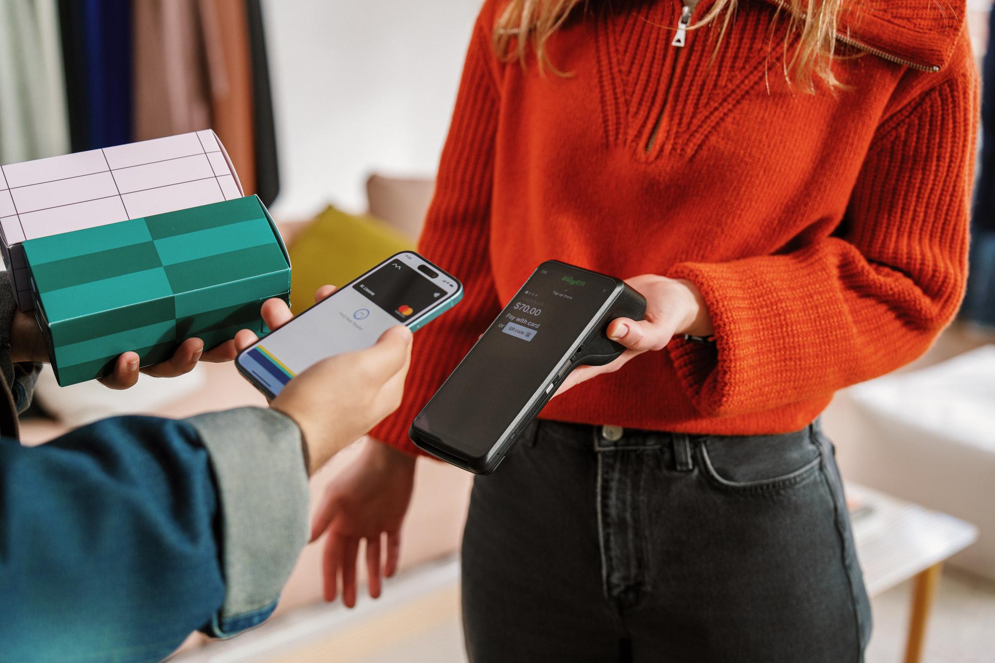 Customer making a contactless payment using an Adyen terminal in a retail setting