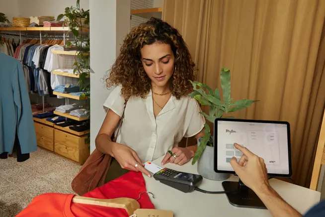 Woman using Adyen payment terminal to process a transaction in a clothing store.