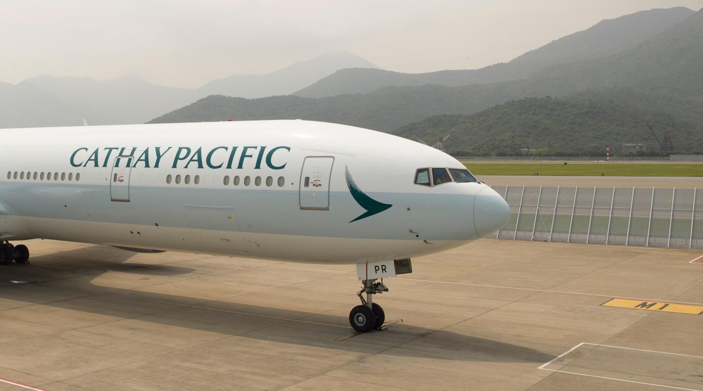 Cathay Pacific aircraft parked on the tarmac with mountains in the background.