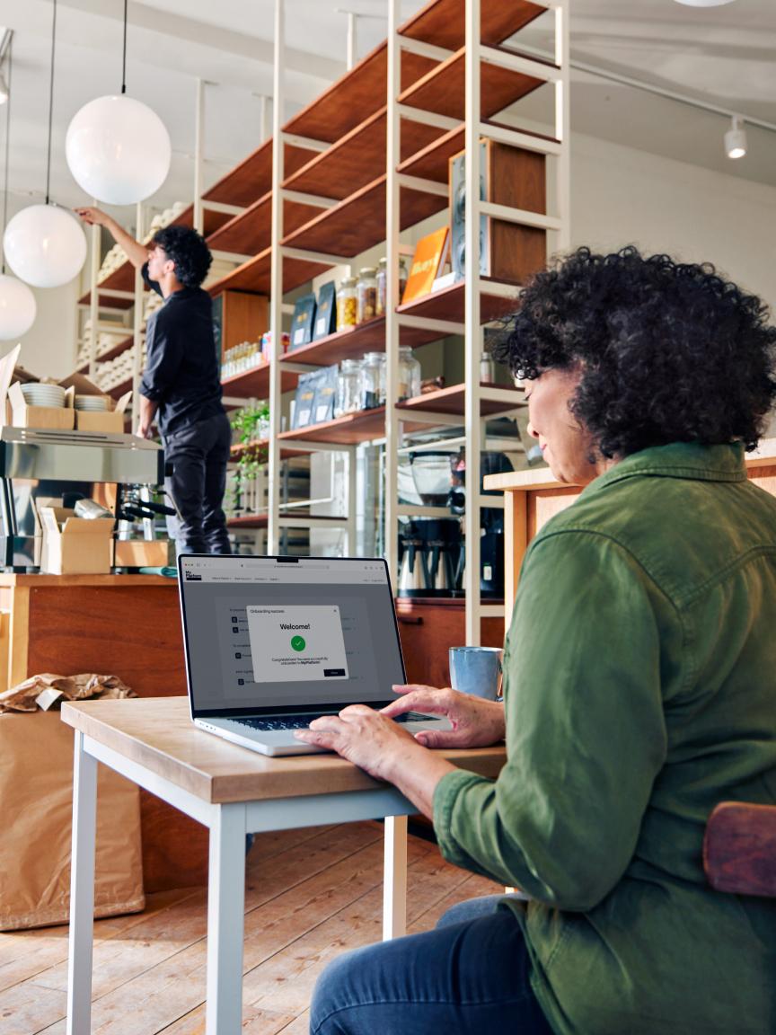 Persoon in een café die op een laptop werkt met het Adyen-betalingsgateway