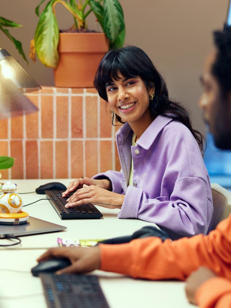 Dva kolegové pracující u stolu s počítačem.