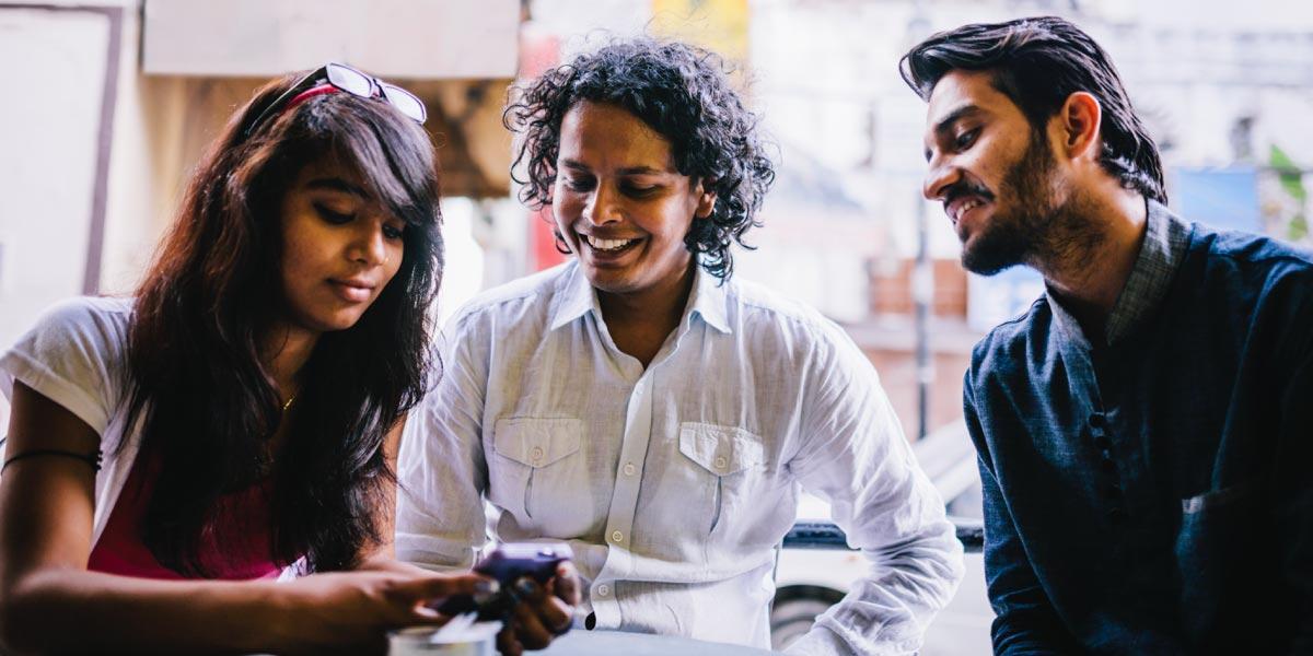 Tres personas examinan un teléfono juntas con interés.