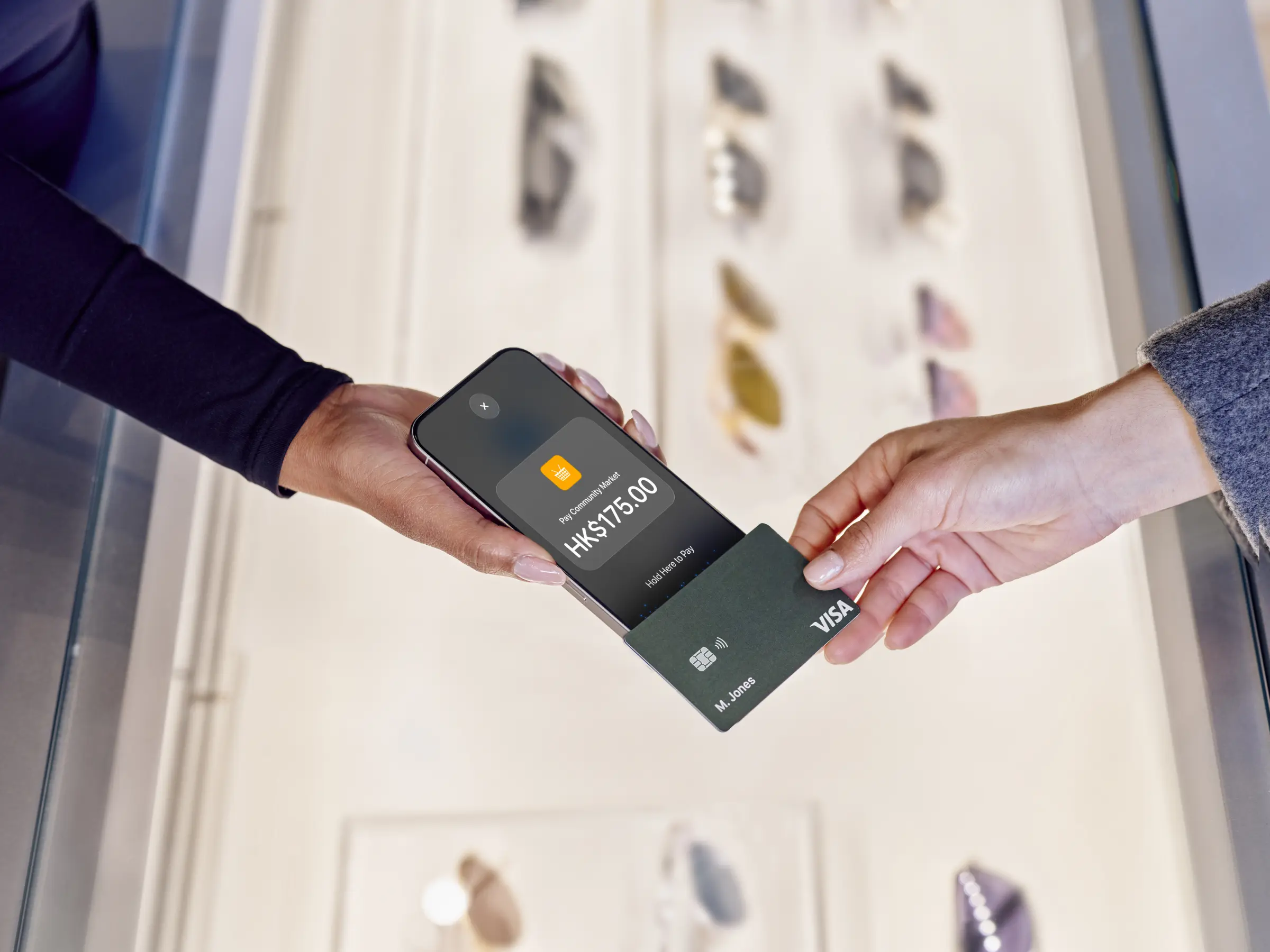 Hand holding a phone with Adyen payment app, a card being tapped for contactless payment.