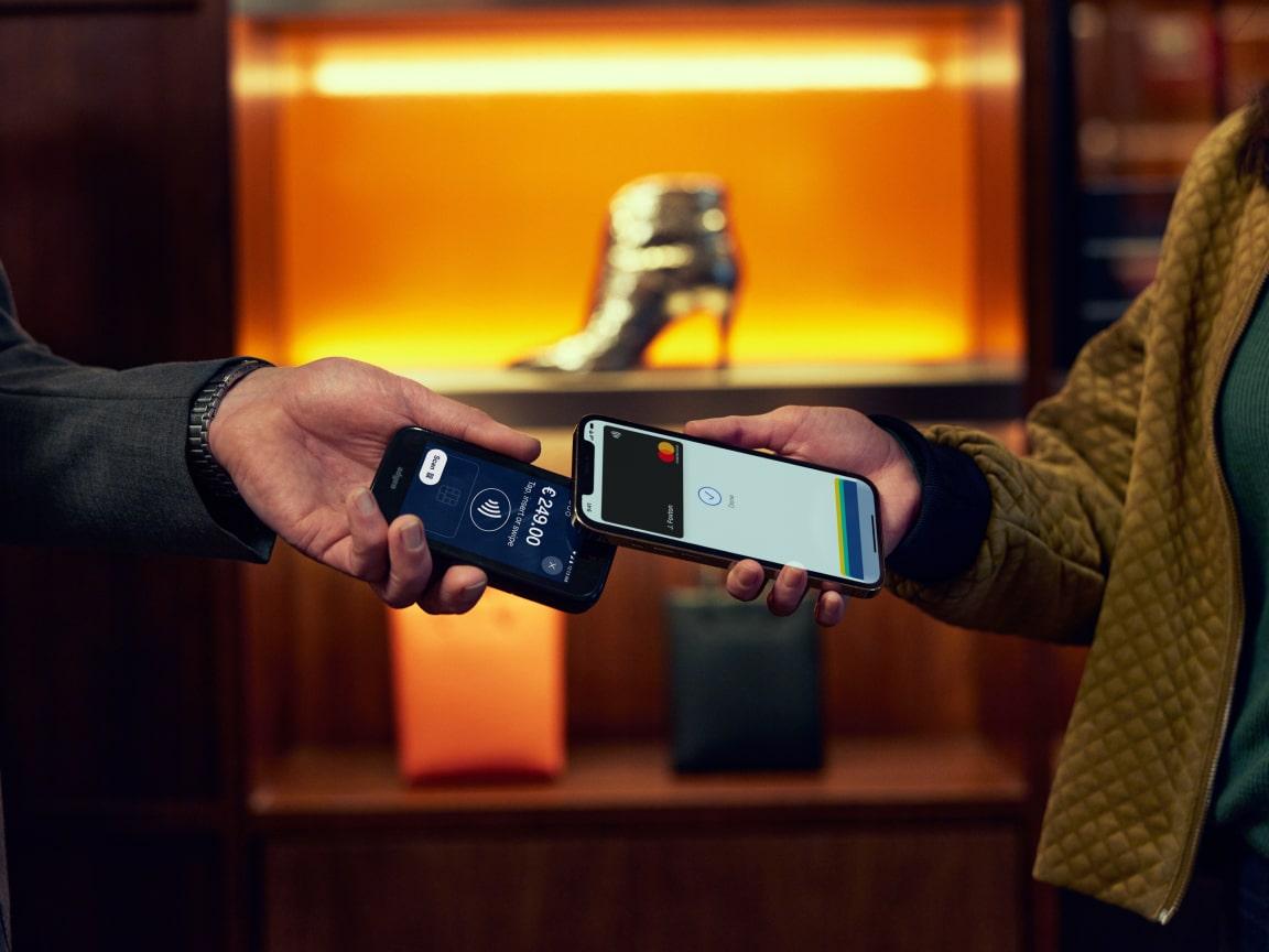 Two people making a contactless payment using smartphones with Adyen interface.