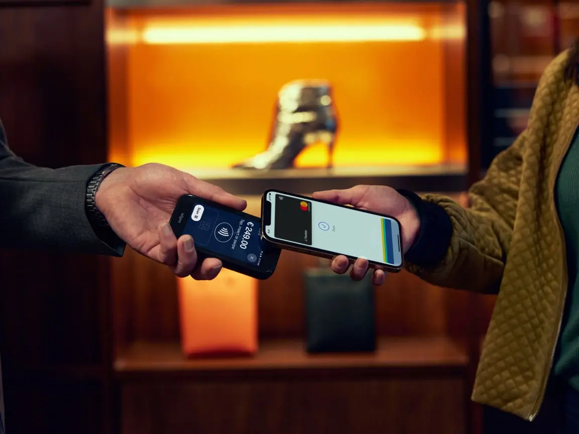 Two people making a contactless payment using smartphones with Adyen interface.