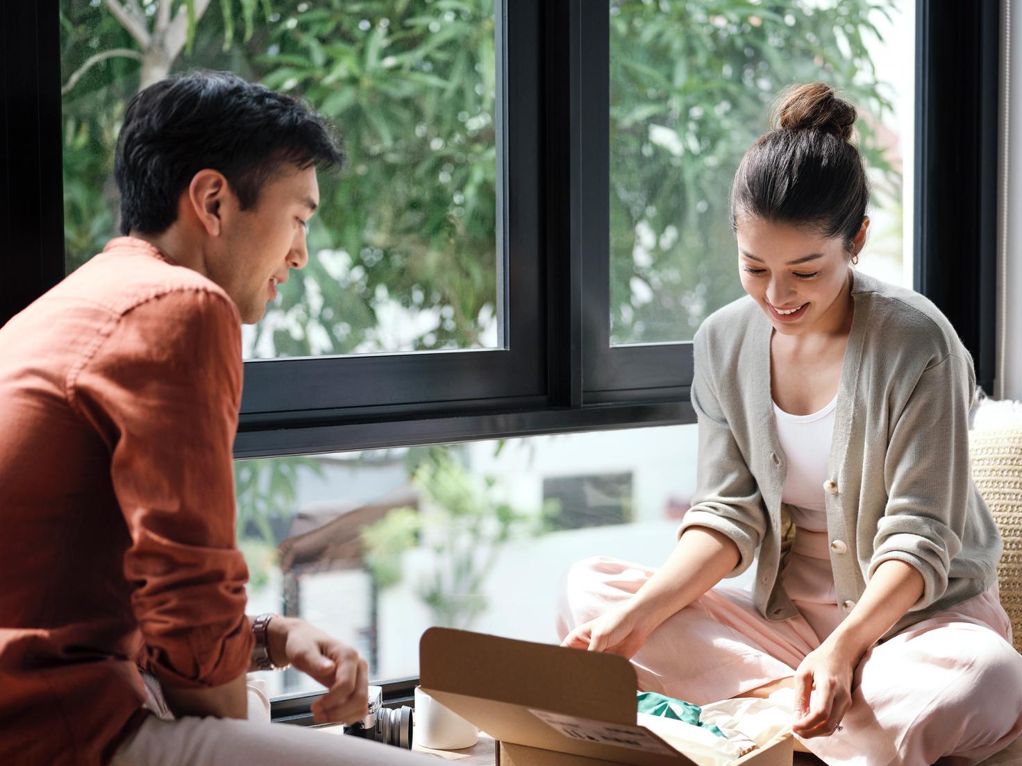 A couple on a windowsill unpacking a box
