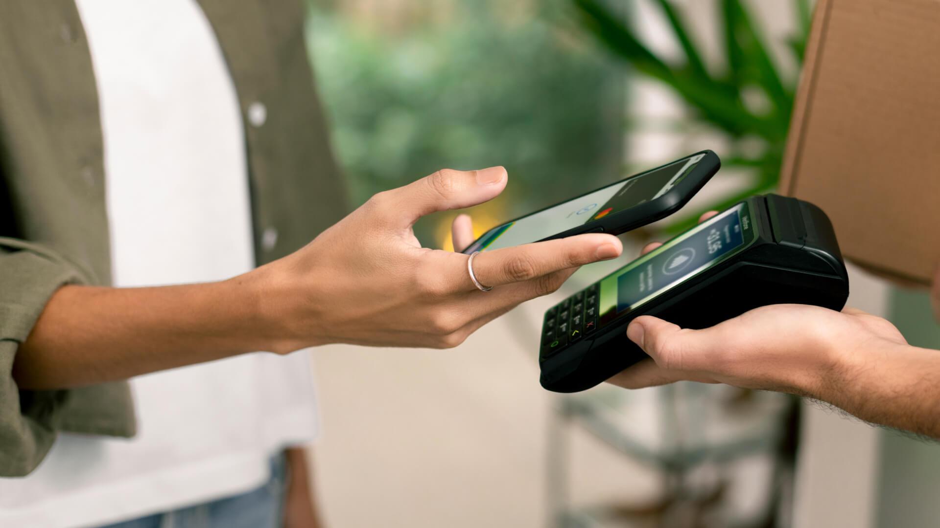Person making a contactless payment using a smartphone to a card reader.