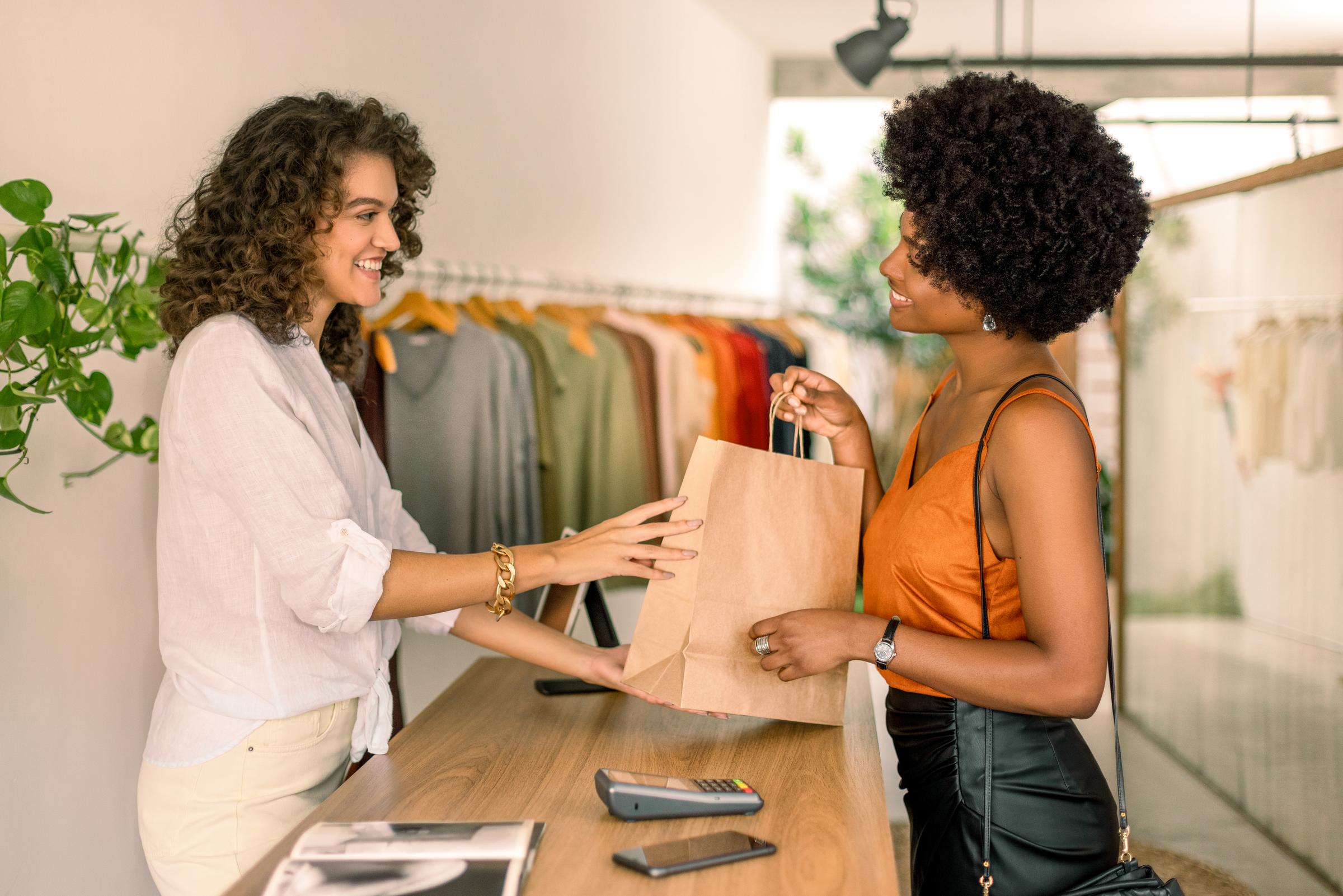 Persona que recibe una bolsa de compras en una tienda de ropa después de pagar en la terminal.