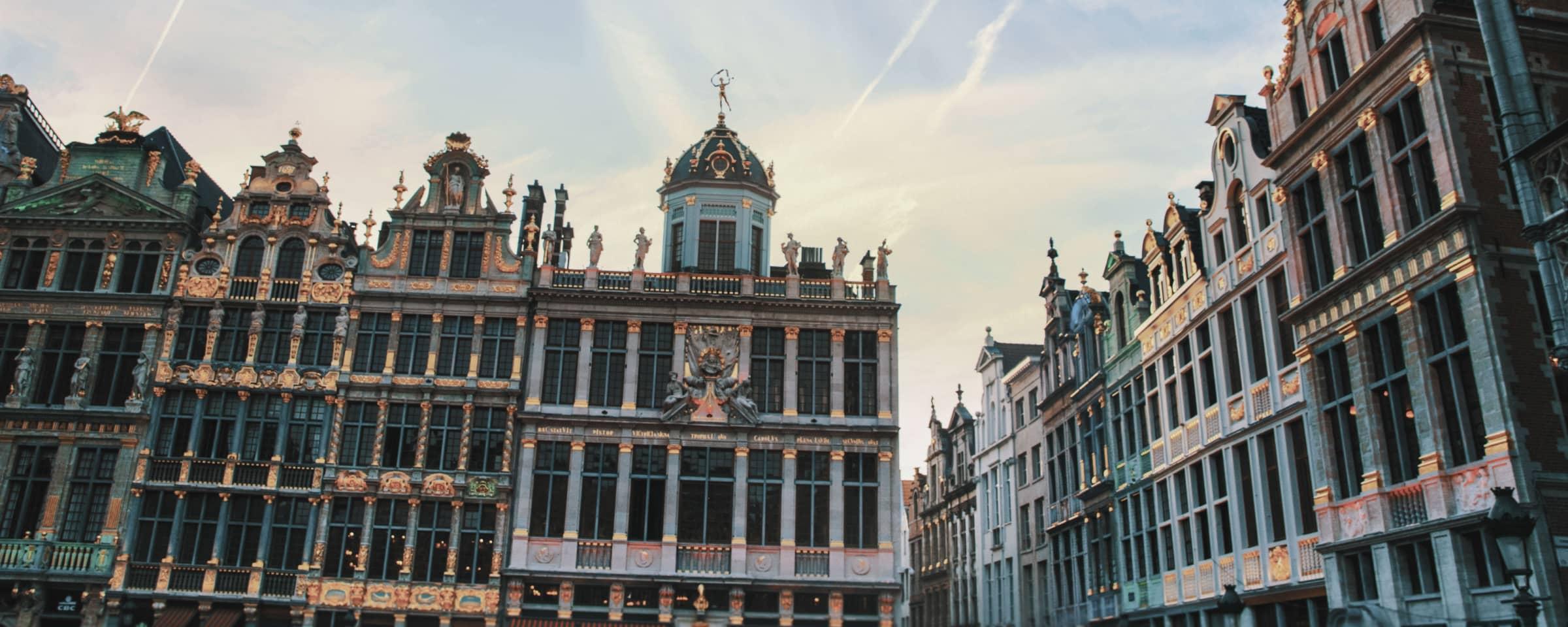 Edificios de la Grand Place con fachadas ornamentadas en Bruselas bajo cielo claro al anochecer.