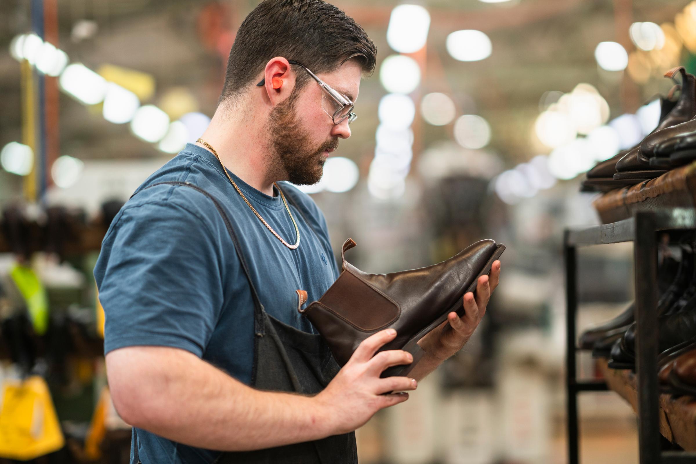 A craftman holding a leather booth 
