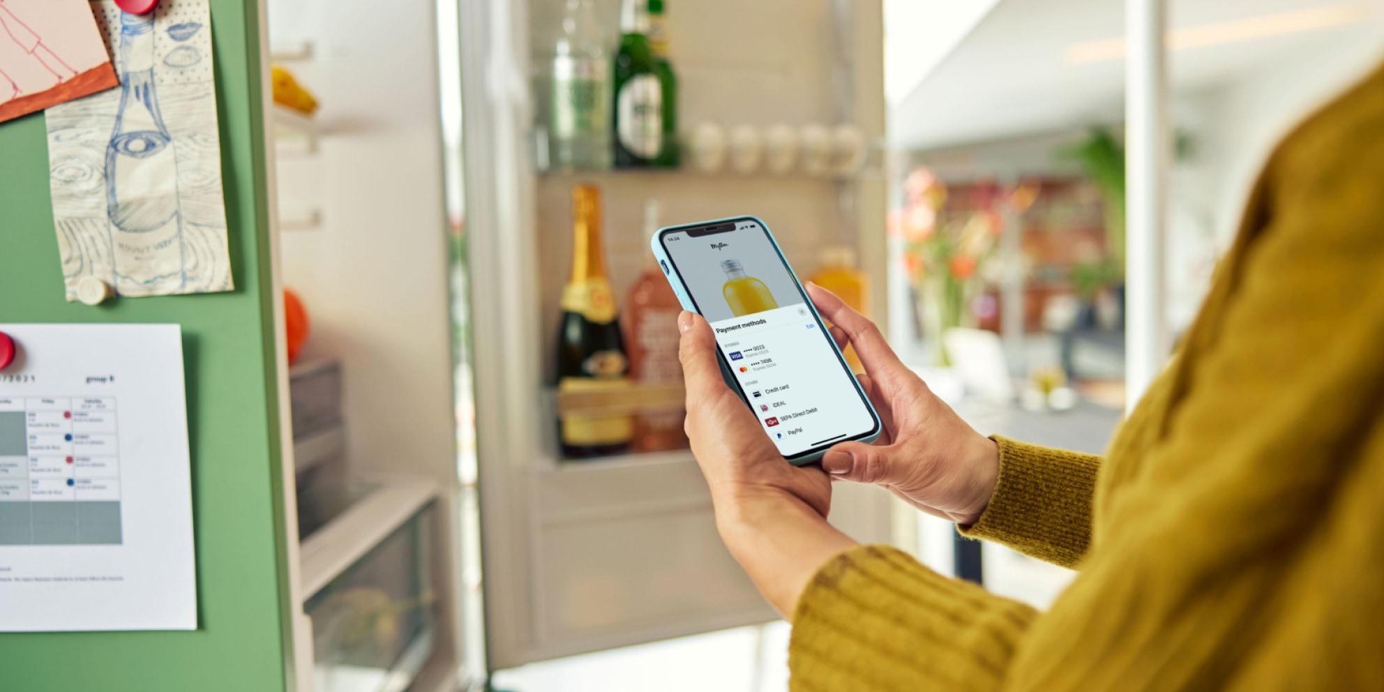Personne utilisant un smartphone affichant une application de paiement numérique avec plusieurs options de carte.