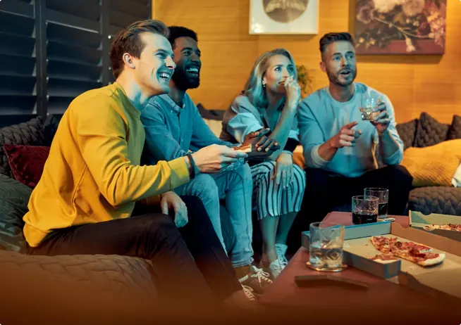 Four friends enjoying video games and pizza in a cozy living room.