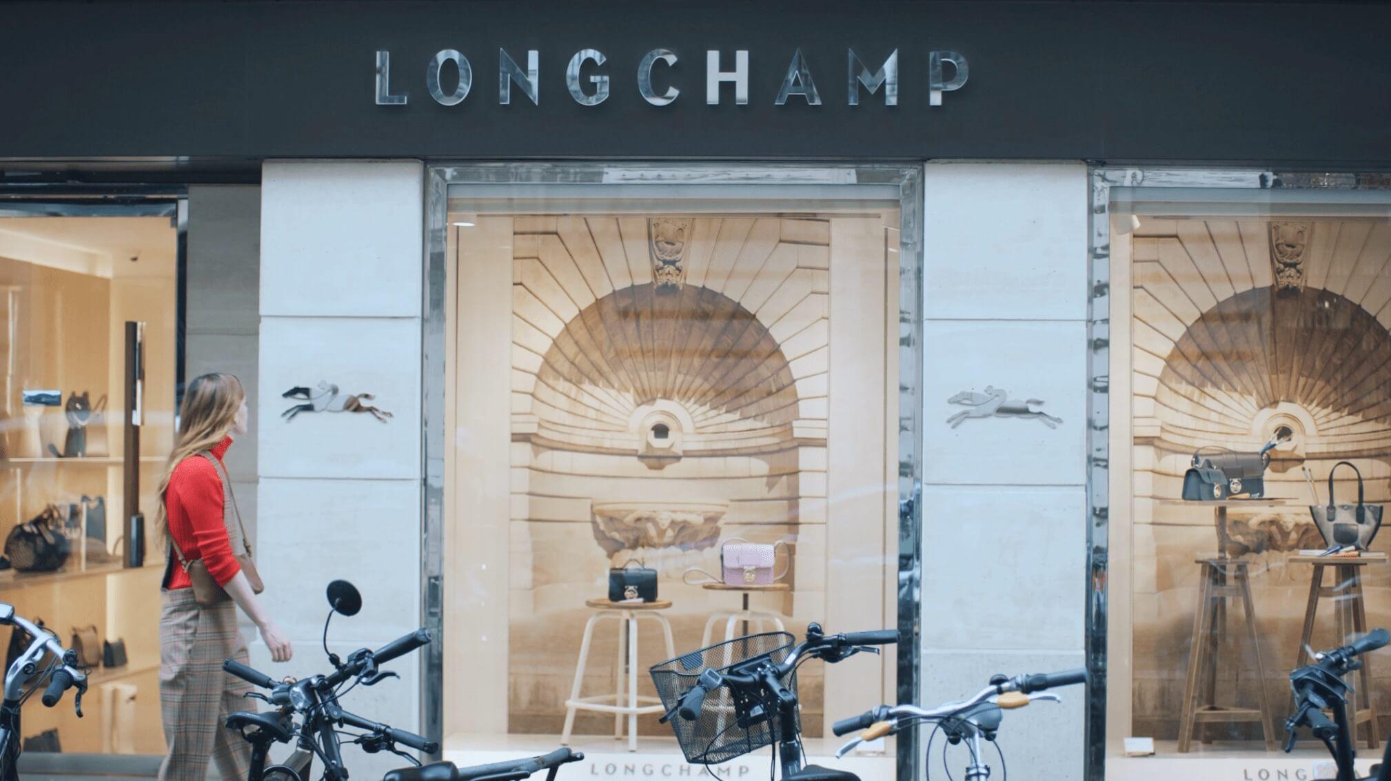Fachada de la tienda Longchamp con persona caminando y bicicletas estacionadas en frente.