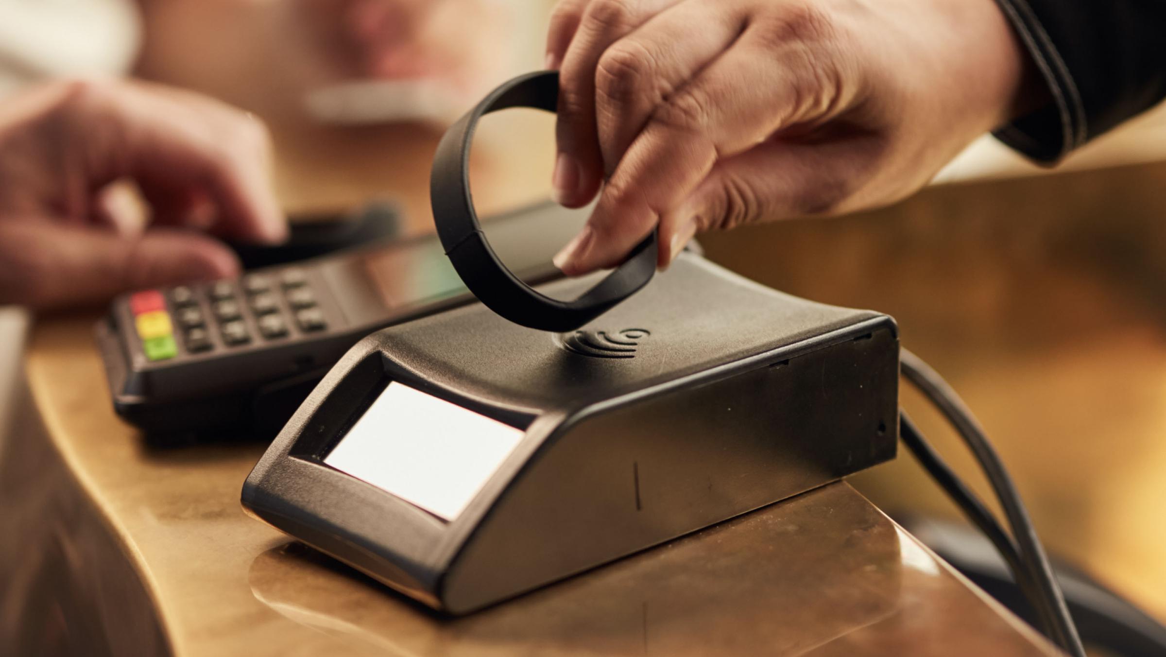 Person using a wearable device to make a contactless payment on an Adyen terminal.