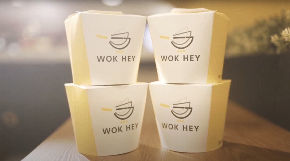 Stacked Wok Hey takeaway food containers on a counter.