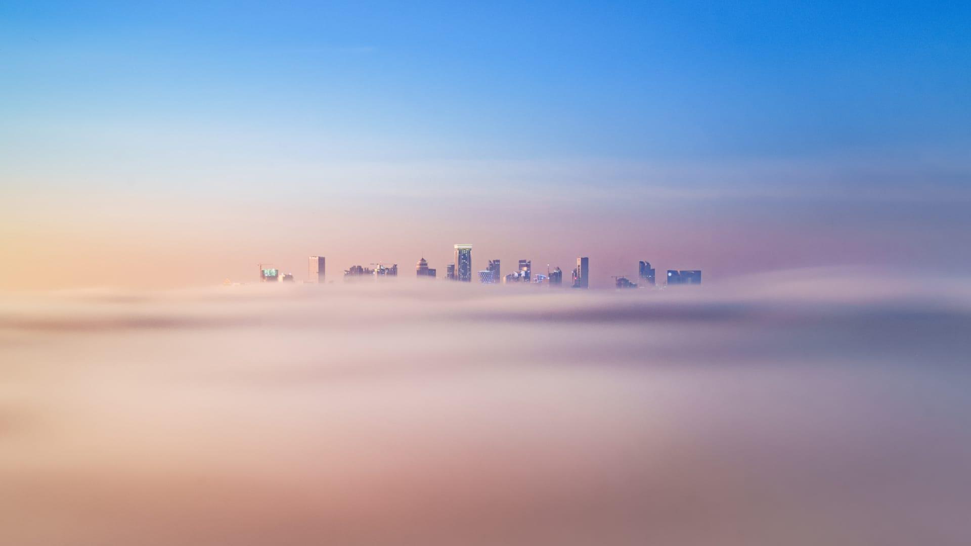 La silueta de la ciudad emerge sobre un manto de nubes de enfoque suave al anochecer en Qatar.