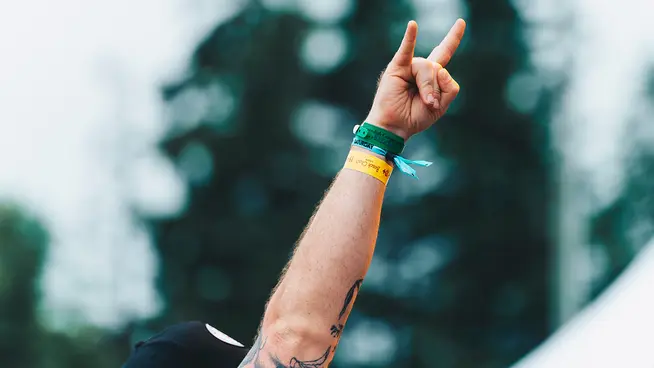 Person's hand up in the air at a concert with wristbands
